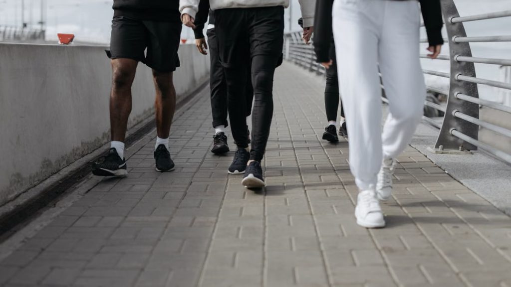 Casual group walk on a city sidewalk, showcasing modern fashion and footwear.